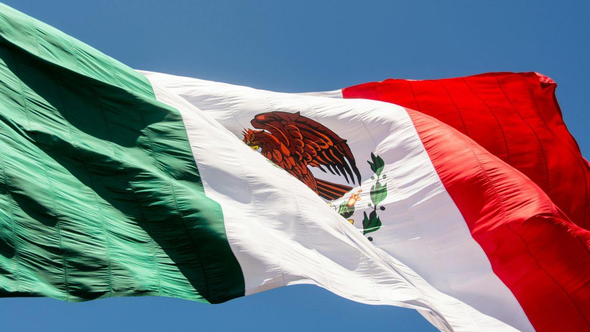 Close-up of the Mexican flag waving in the wind, showing the national emblem with the eagle, snake, and cactus.