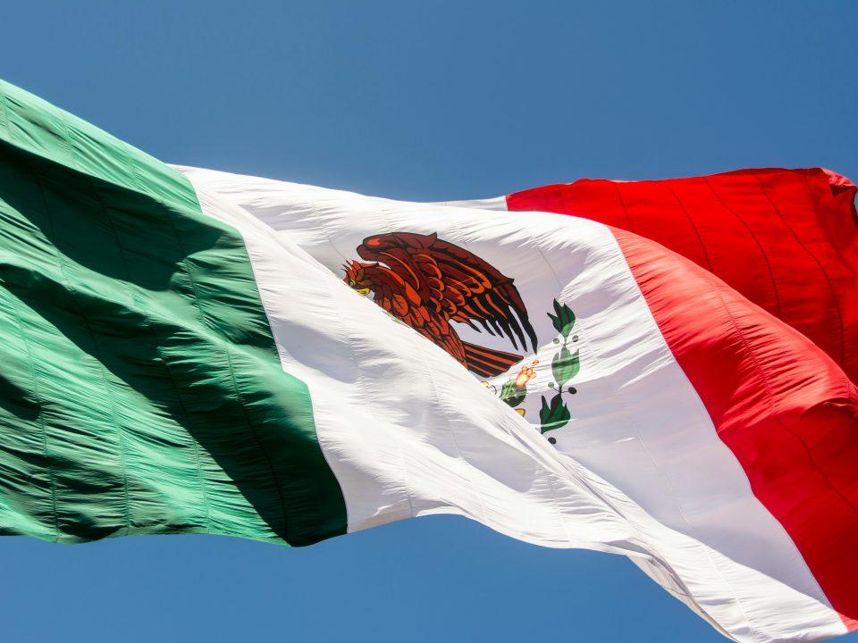Close-up of the Mexican flag waving in the wind, showing the national emblem with the eagle, snake, and cactus.