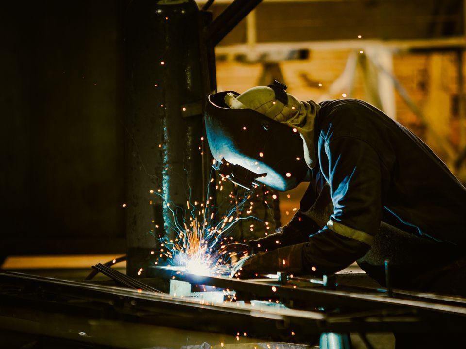 Welder working on steel fabrication, representing metallurgical industries subject to COA reporting requirements in Mexico