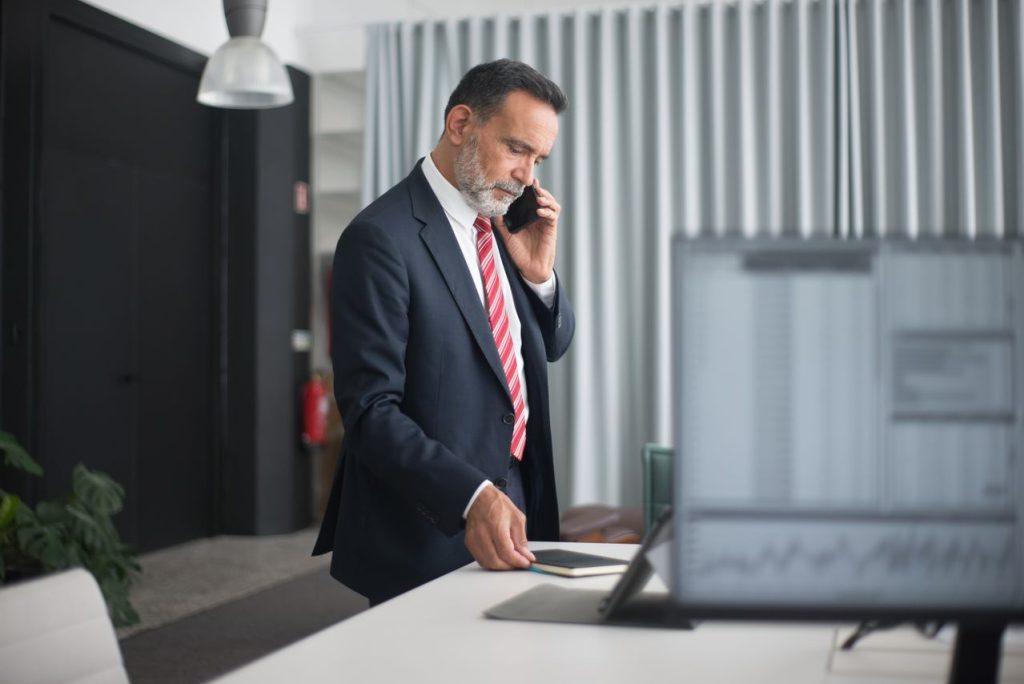Business executive on a phone call while reviewing financial data, representing proactive banking relationship management