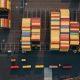 Aerial view of stacked shipping containers at a logistics yard, representing international import and export operations