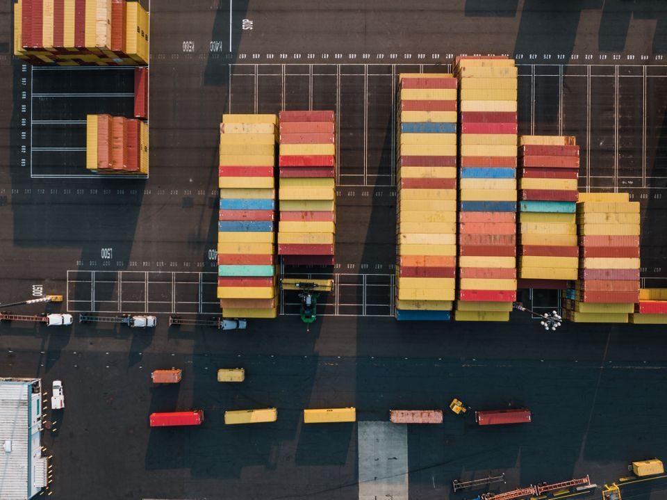 Aerial view of stacked shipping containers at a logistics yard, representing international import and export operations