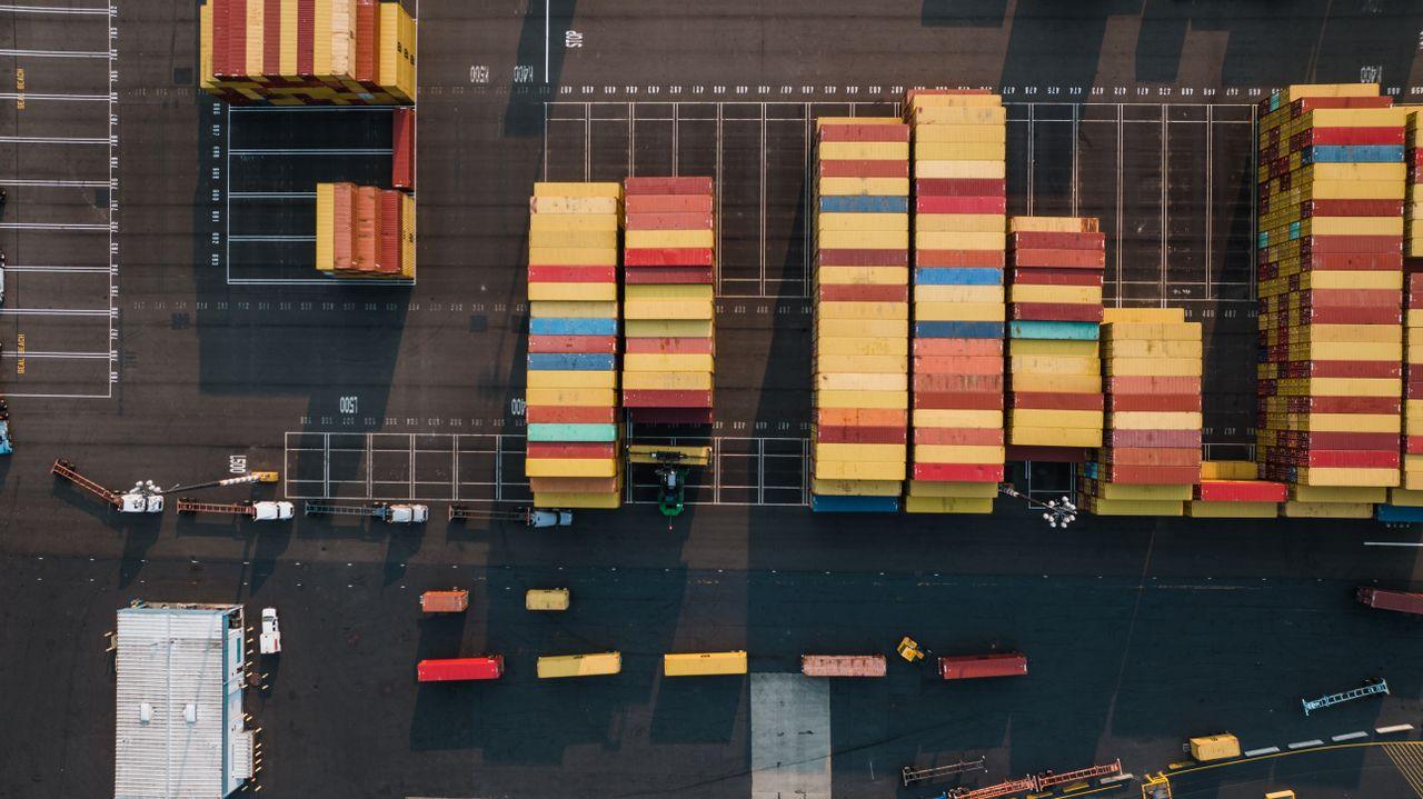 Aerial view of stacked shipping containers at a logistics yard, representing international import and export operations