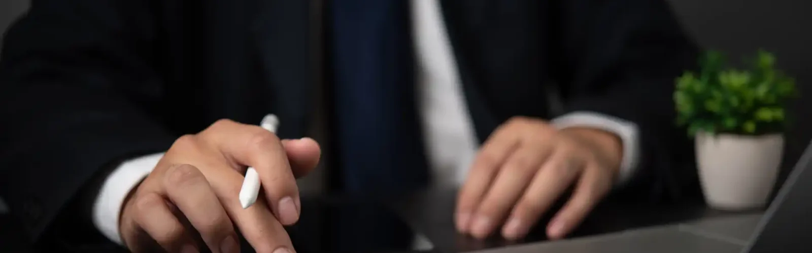 Back Office and Tax Compliance Services for Doing Business in Mexico Business professional calculating financial data on a desk with a calculator, laptop, and plant, representing back office and tax compliance services in Mexico.