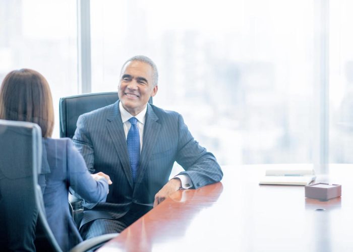 Businessman shaking hands with a colleague in a modern office, representing trust, partnerships, and successful business agreements for companies entering Mexico through soft landing, nearshoring, shelter programs, and IMMEX benefits.