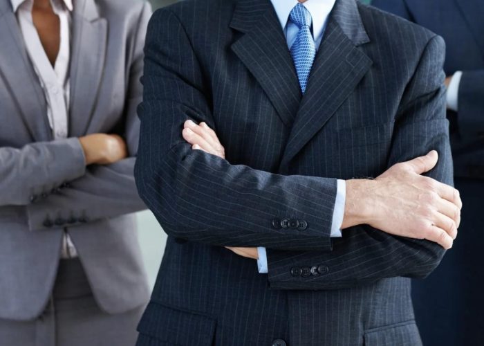 Group of business professionals in formal suits with arms crossed, symbolizing confidence, leadership, and expertise in soft landing, nearshoring, and shelter solutions for companies in Mexico