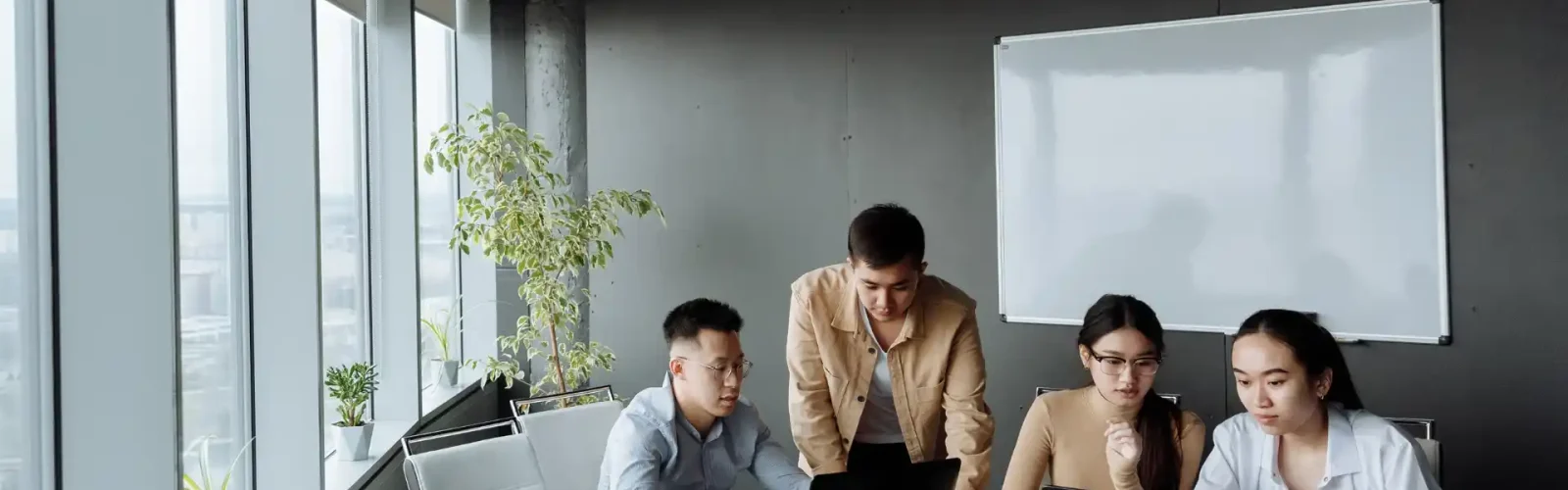 Business team collaborating on laptops in a modern office meeting room at DIMSA, Mexico.